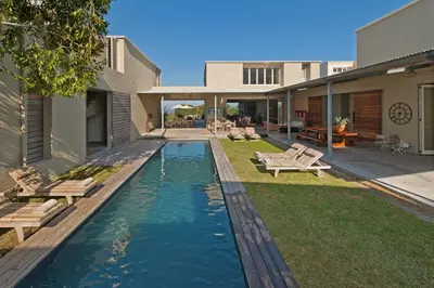 a backyard with a pool with benches and a house at Mosselberg on Grotto Beach in Hermanus