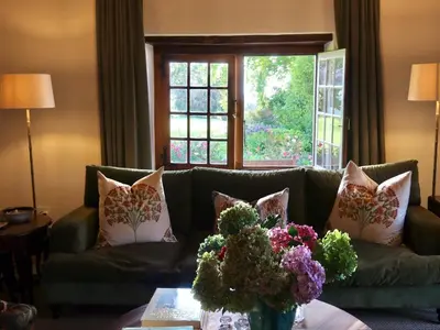 a living room with a green couch with flowers on a table at Navarre Residence in Stellenbosch