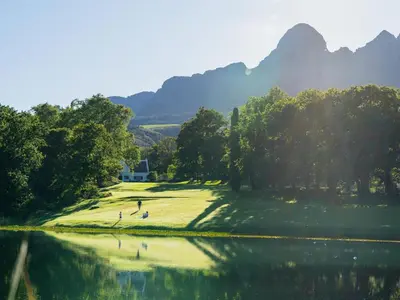 a golf course with a lake and mountains in the background at Navarre Residence in Stellenbosch