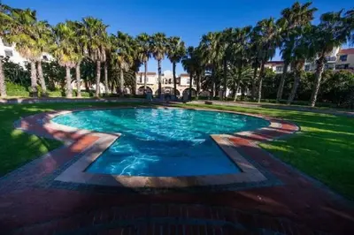 a swimming pool in a park with palm trees at Resort Style Penthouse - BackUp Power in Cape Town