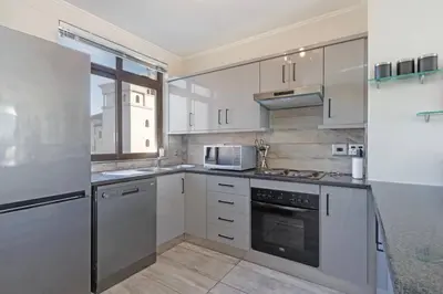 a kitchen with white appliances and a window at Resort Style Penthouse - BackUp Power in Cape Town