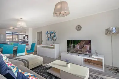a living room with a couch and a tv at Resort Style Penthouse - BackUp Power in Cape Town