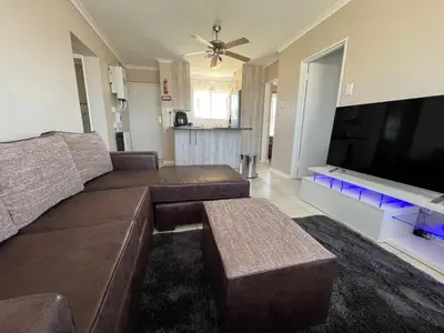 a living room with a brown couch and a flat screen tv at #One6Eight in Hermanus