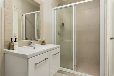 a white bathroom with a sink and a shower at Mayfair 219 in Cape Town