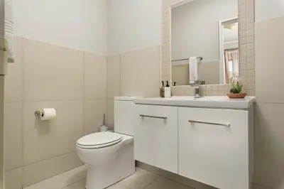 a white bathroom with a toilet and a sink at Mayfair 219 in Cape Town