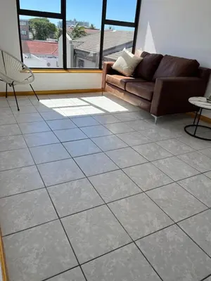 a living room with a couch and a tiled floor at Top Floor Executive apartment in Cape Town