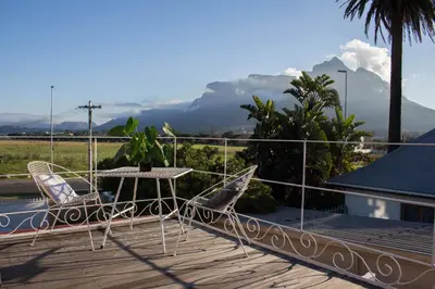 a patio with a table and chairs on a deck at Loft with views in Cape Town