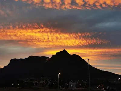 a sunset over a mountain in front of a city at Loft with views in Cape Town
