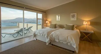 a bedroom with two beds and a balcony with a view at Bayview in Gordonʼs Bay