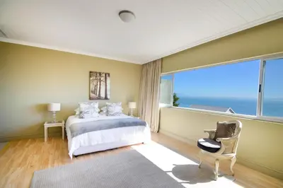 a bedroom with a bed and a large window at Bayview in Gordonʼs Bay