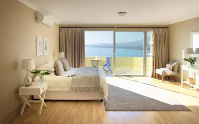 a bedroom with a bed and a view of the ocean at Bayview in Gordonʼs Bay