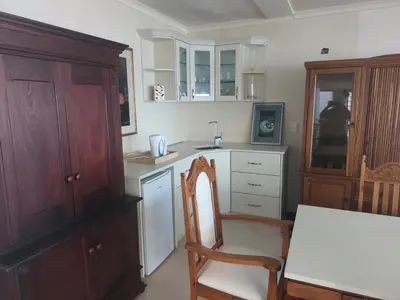 a kitchen with a table and a chair and a sink at The Waves of Schulphoek in Hermanus