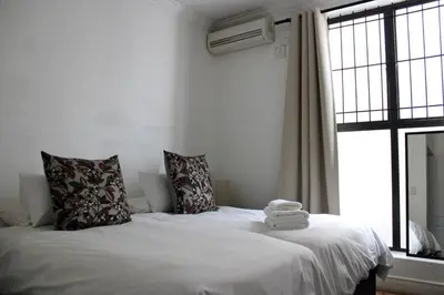 a bedroom with a white bed with towels on it at Contemporary Central Apartment by ARPA Hospitalities in Stellenbosch