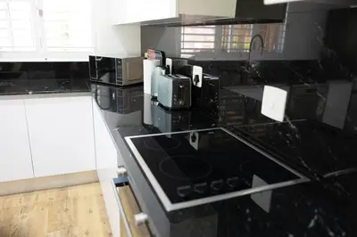 a kitchen with a black counter top with microwaves at Garten Wohnung mit Pool, 2 Schlafzimmer in Cape Town