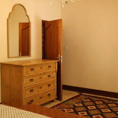 a bedroom with a dresser and a mirror and a door at Kleinhof in Franschhoek