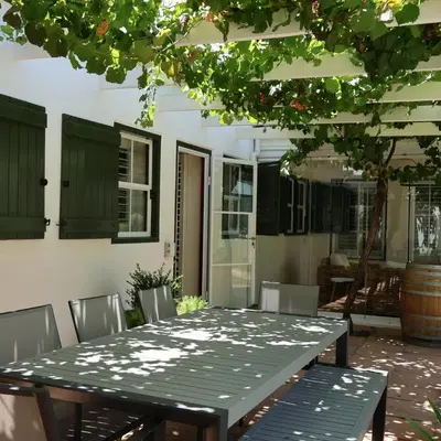 a table and chairs in a patio with a tree at Kleinhof in Franschhoek