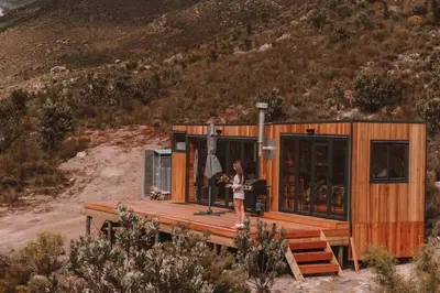 a woman standing on the deck of a tiny house at Luxury Solace Cabin - River Cabin in Rawsonville