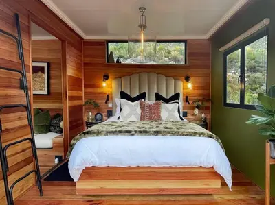 a bedroom with a bed in a room with wooden walls at Luxury Solace Cabin - River Cabin in Rawsonville