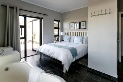 a bedroom with a bed and a bathroom with a tub at Vue La Mer in Hermanus
