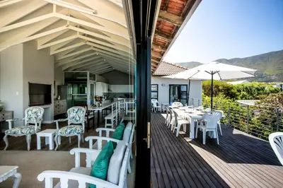 a restaurant with white tables and chairs on a deck at Vue La Mer in Hermanus
