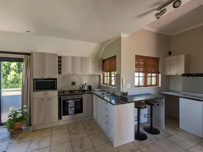 a large kitchen with white cabinets and counters at 33 Longifolia in Stellenbosch