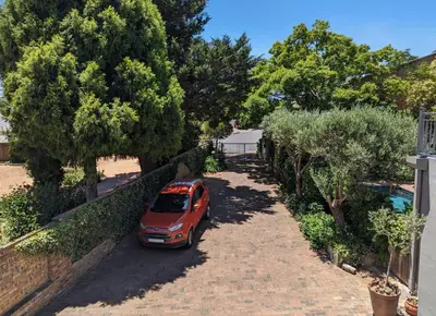 a red car parked in a driveway next to trees at 33 Longifolia in Stellenbosch