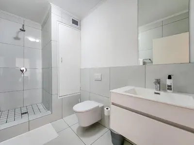 a white bathroom with a toilet and a sink at Pool, Gym, self check-in,Parking in Cape Town