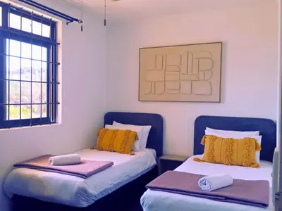 a room with two beds with yellow pillows at Pool, Gym, self check-in,Parking in Cape Town