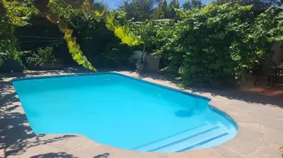 a blue swimming pool in a yard with trees at Linge Longa in Worcester