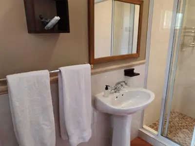 a bathroom with a sink and a shower with towels at Dai Heka Guest House in Strand