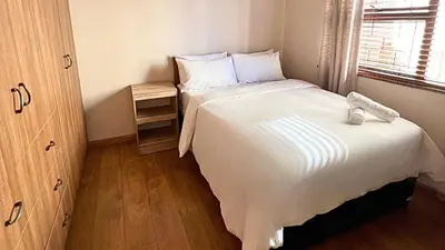 a small bedroom with a large bed and a window at Kabana Family Home and Guest House in Cape Town