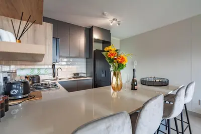 a kitchen with a table with chairs and a vase with flowers at Chic Modern 2 bedroom beachfront with views, 6 Blue Tides in Bloubergstrand