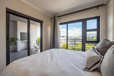 a bedroom with a large bed and a large window at Chic Modern 2 bedroom beachfront with views, 6 Blue Tides in Bloubergstrand