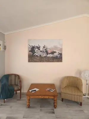 a living room with a table and a painting of cows at Thys' Place in Cape Town