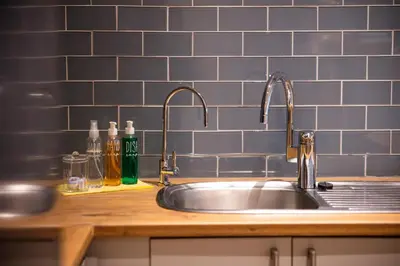 a sink in a kitchen with blue tiles on the wall at 505 La Roche, Paarl in Paarl