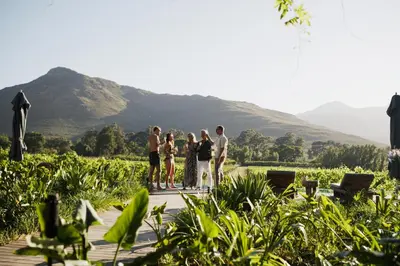 a group of people standing on a wooden deck with mountains in the background at MAISON FRANSCHHOEK in Franschhoek
