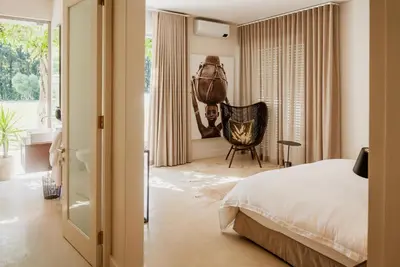 a bedroom with a bed and a chair and a window at MAISON FRANSCHHOEK in Franschhoek
