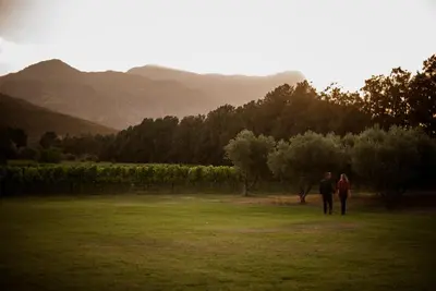 two people walking in a field with mountains in the background at MAISON FRANSCHHOEK in Franschhoek