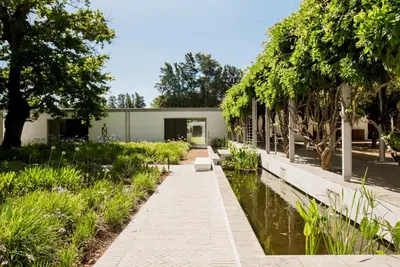a garden with a pond and trees and a building at MAISON FRANSCHHOEK in Franschhoek