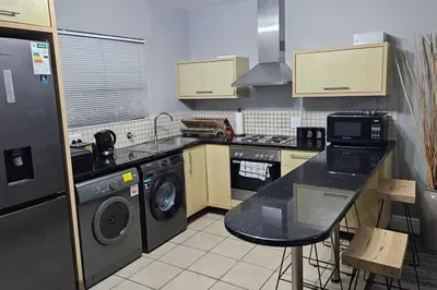 a kitchen with a stove and a sink and a dishwasher at SS Luxury Apartments in Cape Town