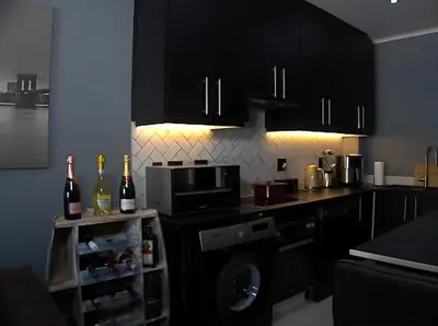 a kitchen with black cabinets and bottles of wine at Sitari County Estate - The Most Iconic Estate in Cape Town