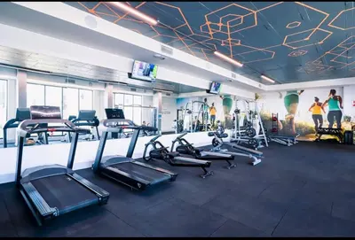 a gym with several tread machines and people in the background at Sitari County Estate - The Most Iconic Estate in Cape Town