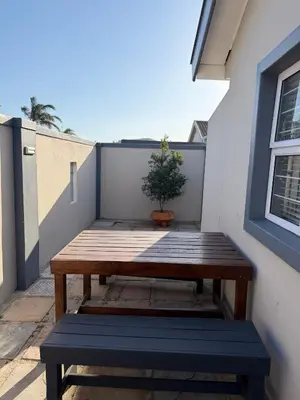 a wooden bench on a balcony with a potted plant at Entertainers delight near the beach & wine routes in Cape Town
