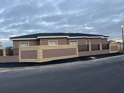 a brown house with a fence and a street at West Coast comfortable stays in Cape Town