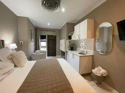 a bedroom with a large bed and a kitchen at DOMIN LUXURY SUITES in Cape Town