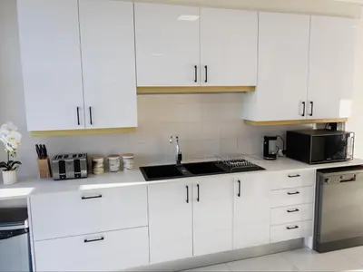 a white kitchen with white cabinets and a sink at St Tropez Beachfront 101 in Strand