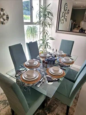 a dining room table with chairs and a glass table top at Spray Villa Bloubergstrand with hot tub and close to the beach in Bloubergstrand