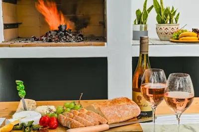 a table with two glasses of wine and food at Spray Villa Bloubergstrand with hot tub and close to the beach in Bloubergstrand