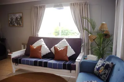a couch with pillows sitting in front of a window at Ocean Escape in Strand