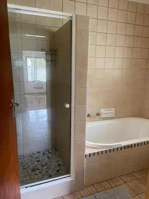 a bathroom with a tub and a shower with a glass door at A cosy home in Hermanus in Hermanus